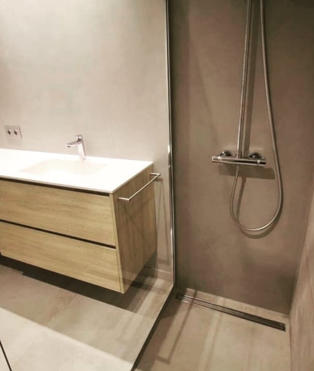 Baño en microcemento con mueble de madera y ducha