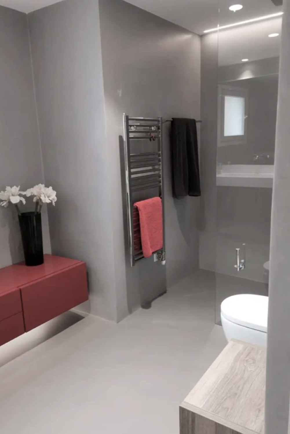 Baño en microcemento gris con detalles en rojo
