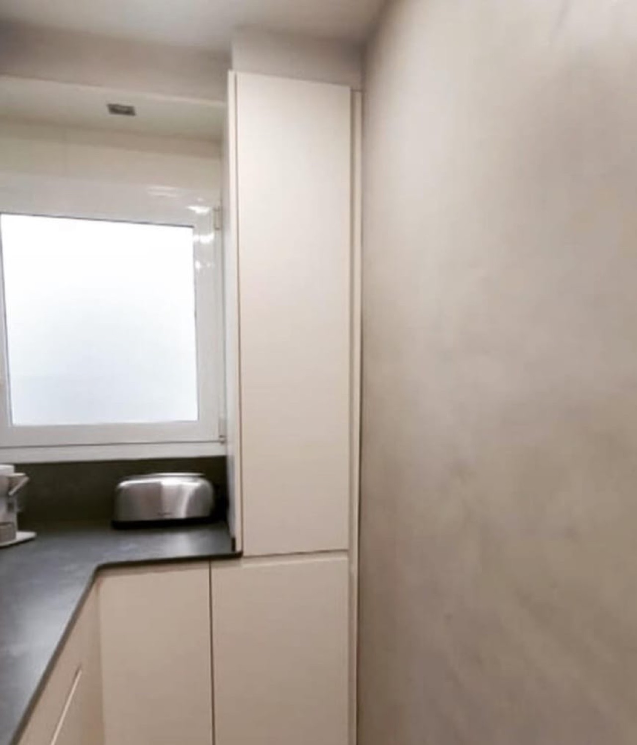 Cocina blanca con pared de microcemento beige