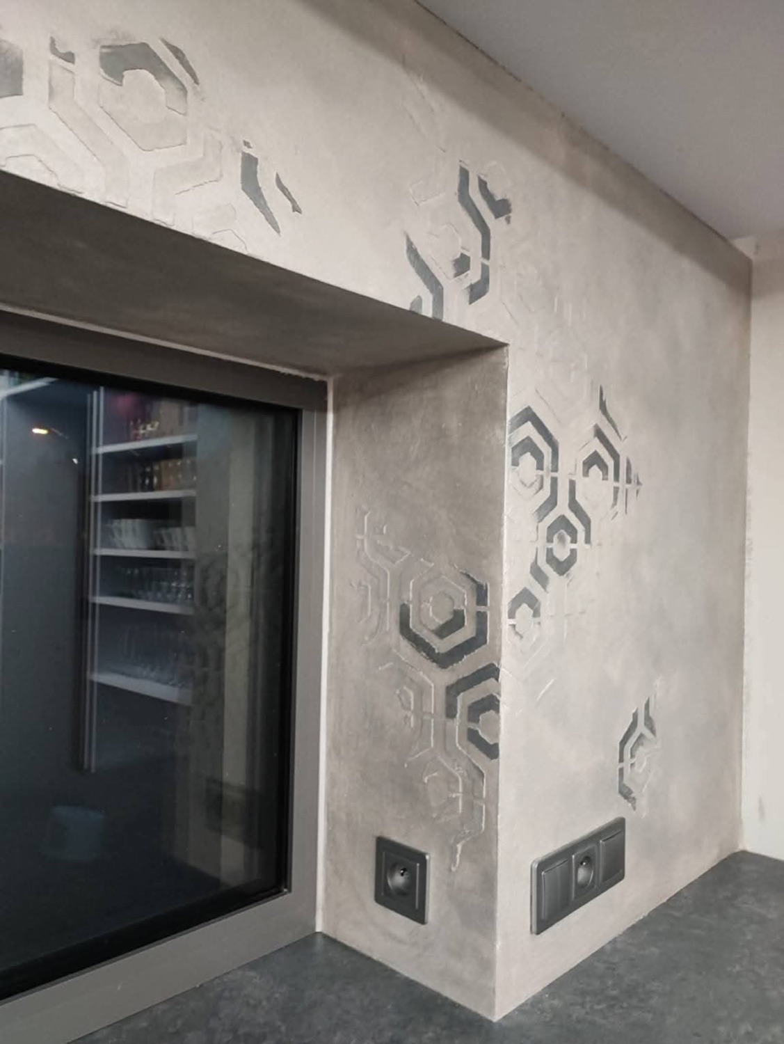 Pared de microcemento gris con patrón de hexágonos
